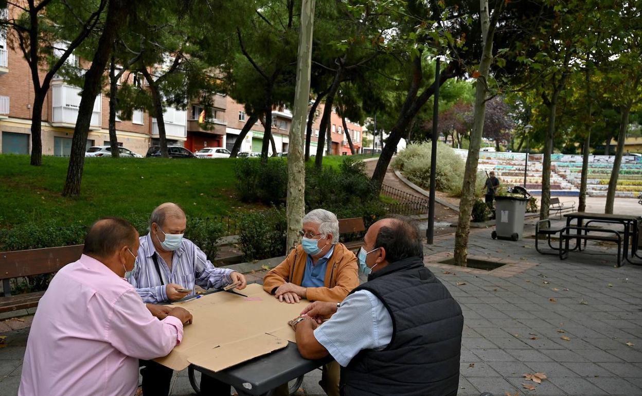 Un grupo de ciudadanos juega a las cartas en un parque. 