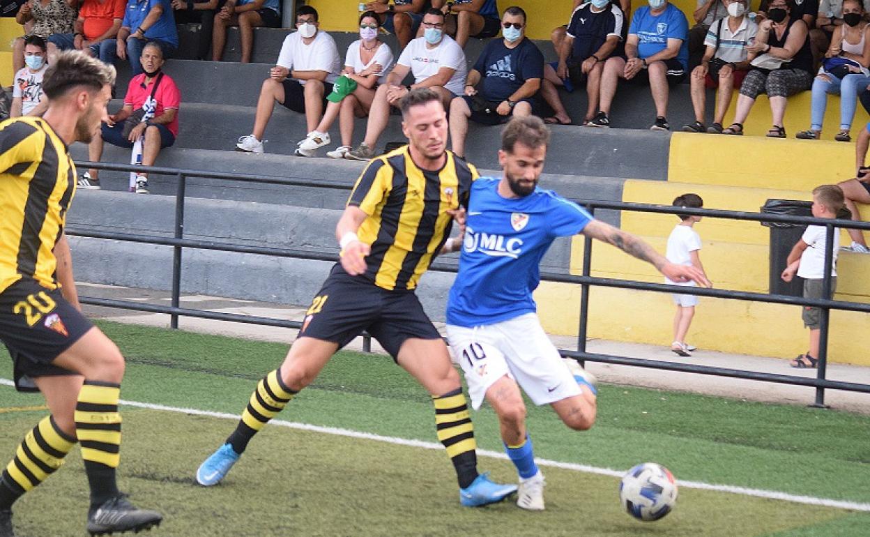 Fran Carnicer pegado a la banda y protegiendo el balón ante la presión de un jugador del San Roque.