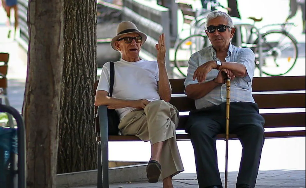 Dos ciudadanos sentados en un banco, disfrutando el tiempo. 
