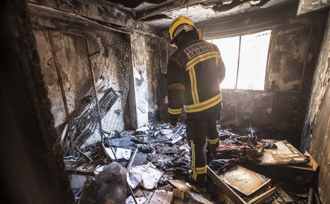 Un bombero inspecciona la habitación de una vivienda calcinada por un incendio