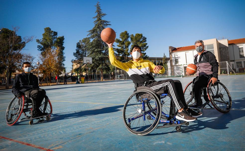 Un jugador del Covirán Churriana Inclusivo enseña a uno de los alumnos a realizar un pase, utilizando una silla de ruedas de competición. 