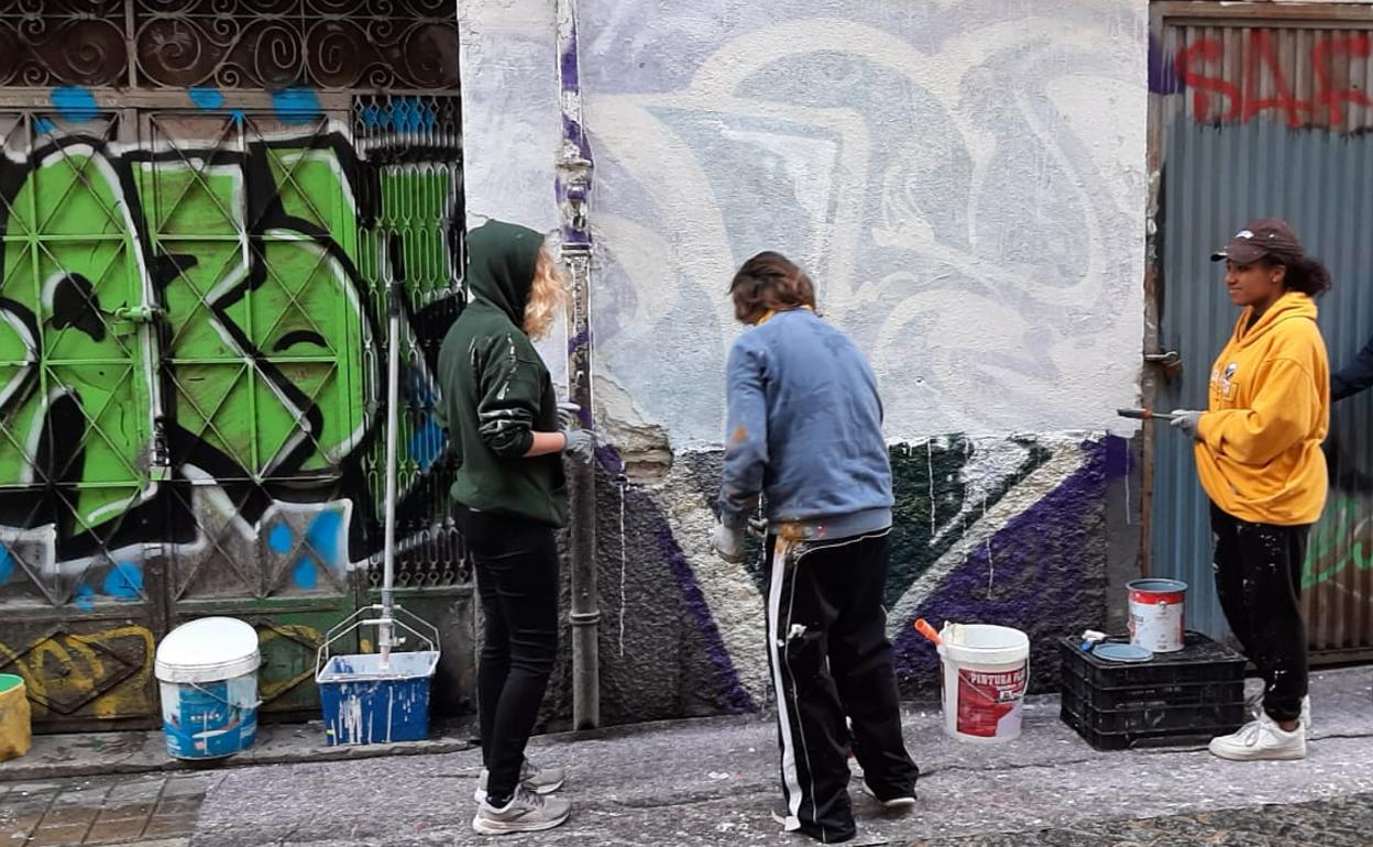Varios vecinos del barrio y estudiantes de API pintando sobre grafitis.
