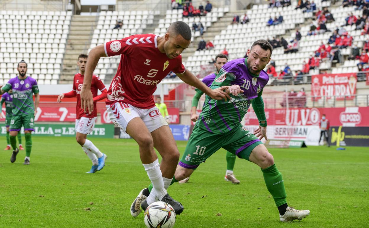 Juanma Espinosa controla el esférico rodeado de jugadores del Real Murcia. 