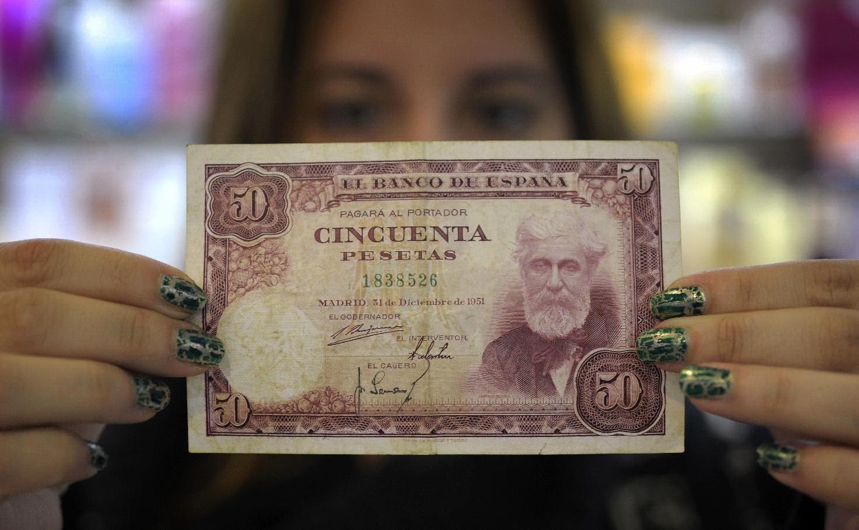 Dependienta de una tienda de Salvaterra de Miño, en Pontevedra, muestra billetes de pesetas