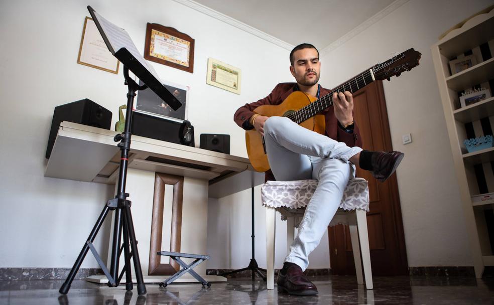 José Fermín rasga las seis cuerdas de su guitarra en el salón de su casa. 