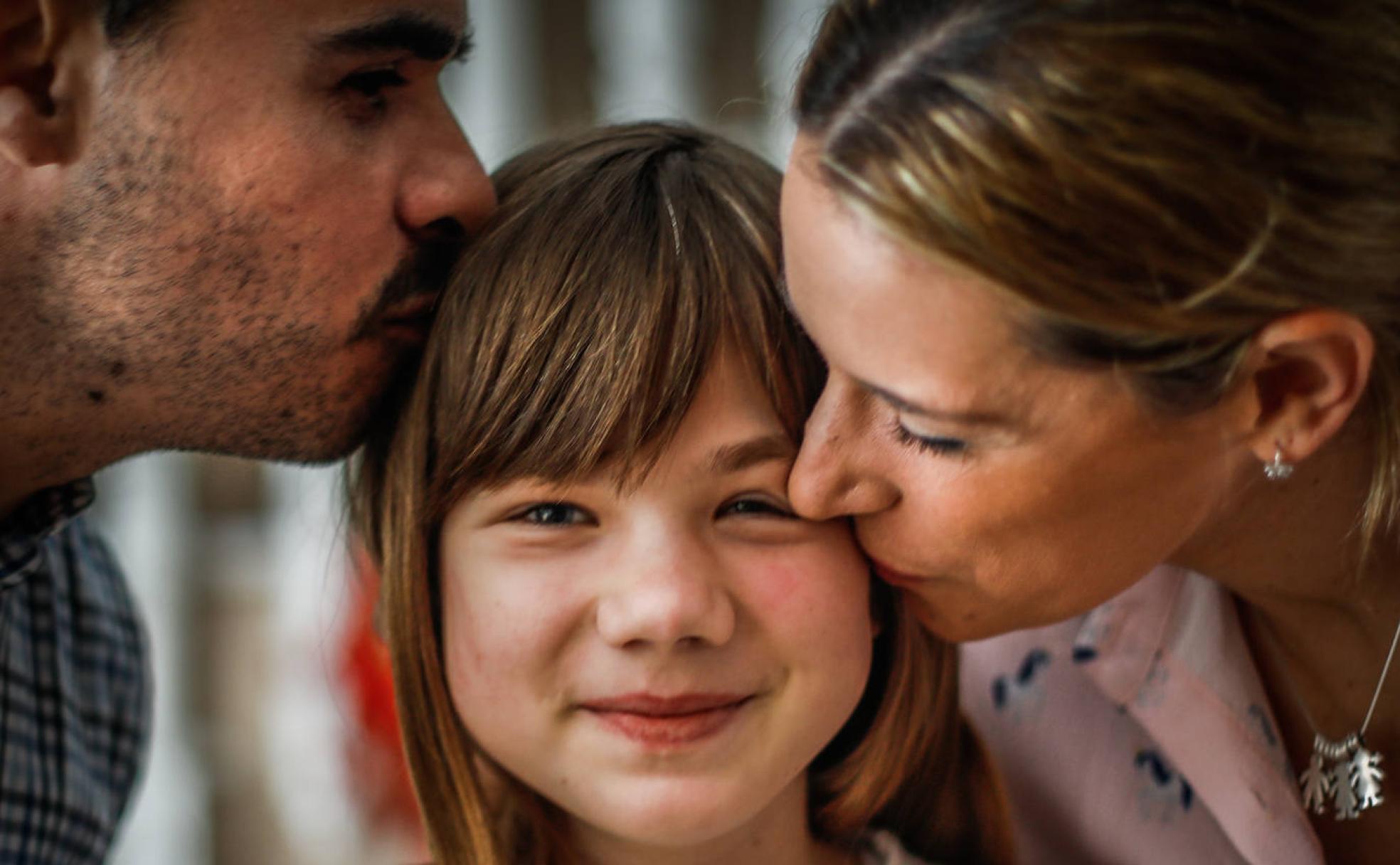 Angelina es besada por su padre y su madre de acogida, Gabriel y Sandra.