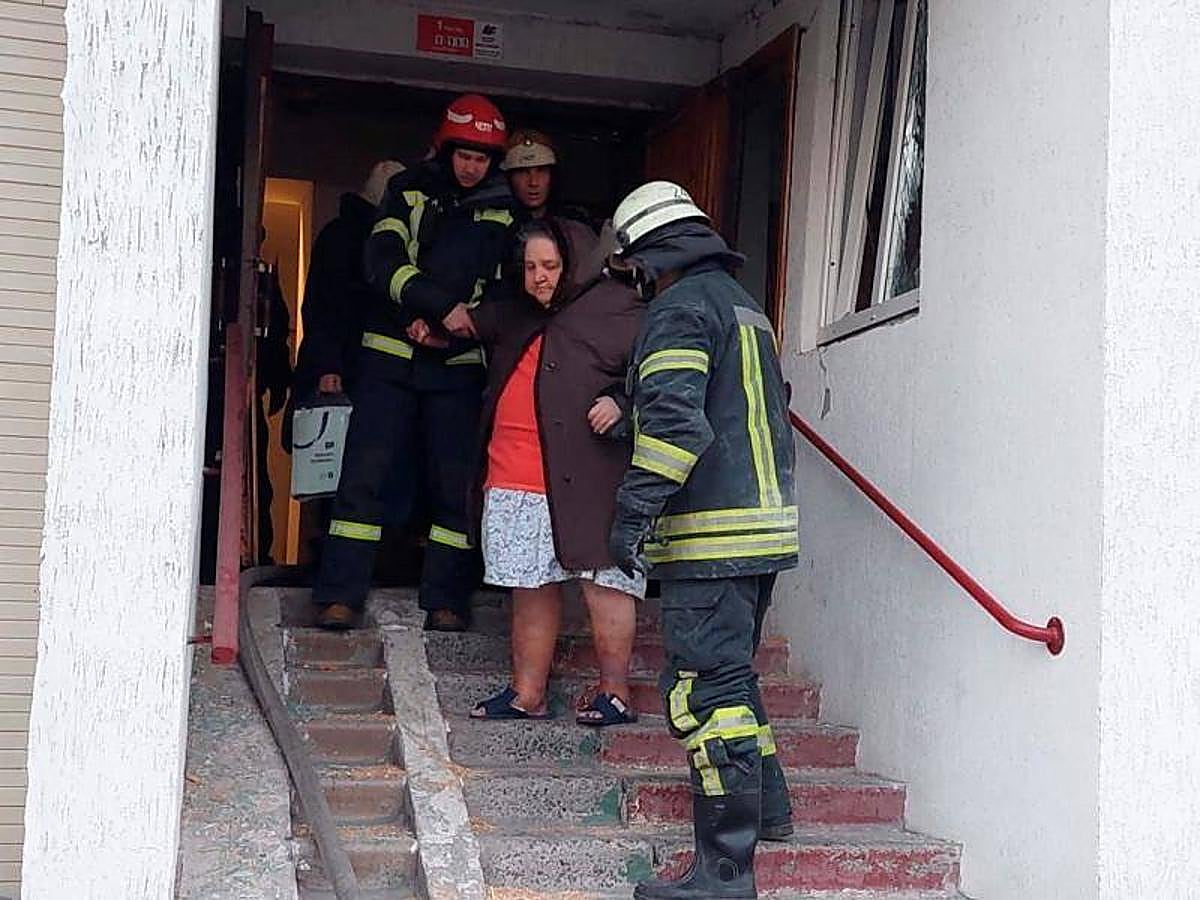 Una mujer es evacuada por miembros del equipo de rescate después de que los restos de un misil derribado dañaran un edificio residencial.