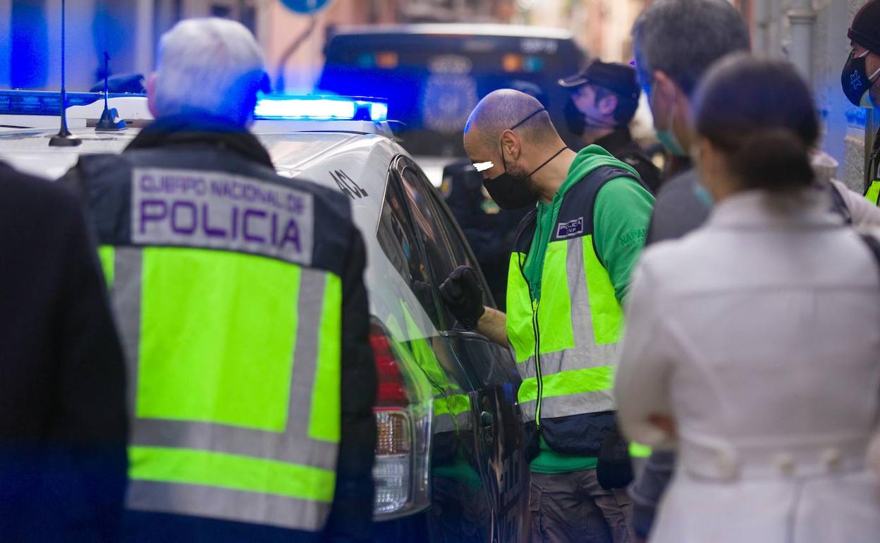 Un agente de Policía Nacional habla con el detenido a través de la ventanilla del coche policial la tarde del miércoles, momentos antes de que iniciaran el registro en la casa okupa donde residía el arrestado en la calle Concepción 18 de la capital granadina.
