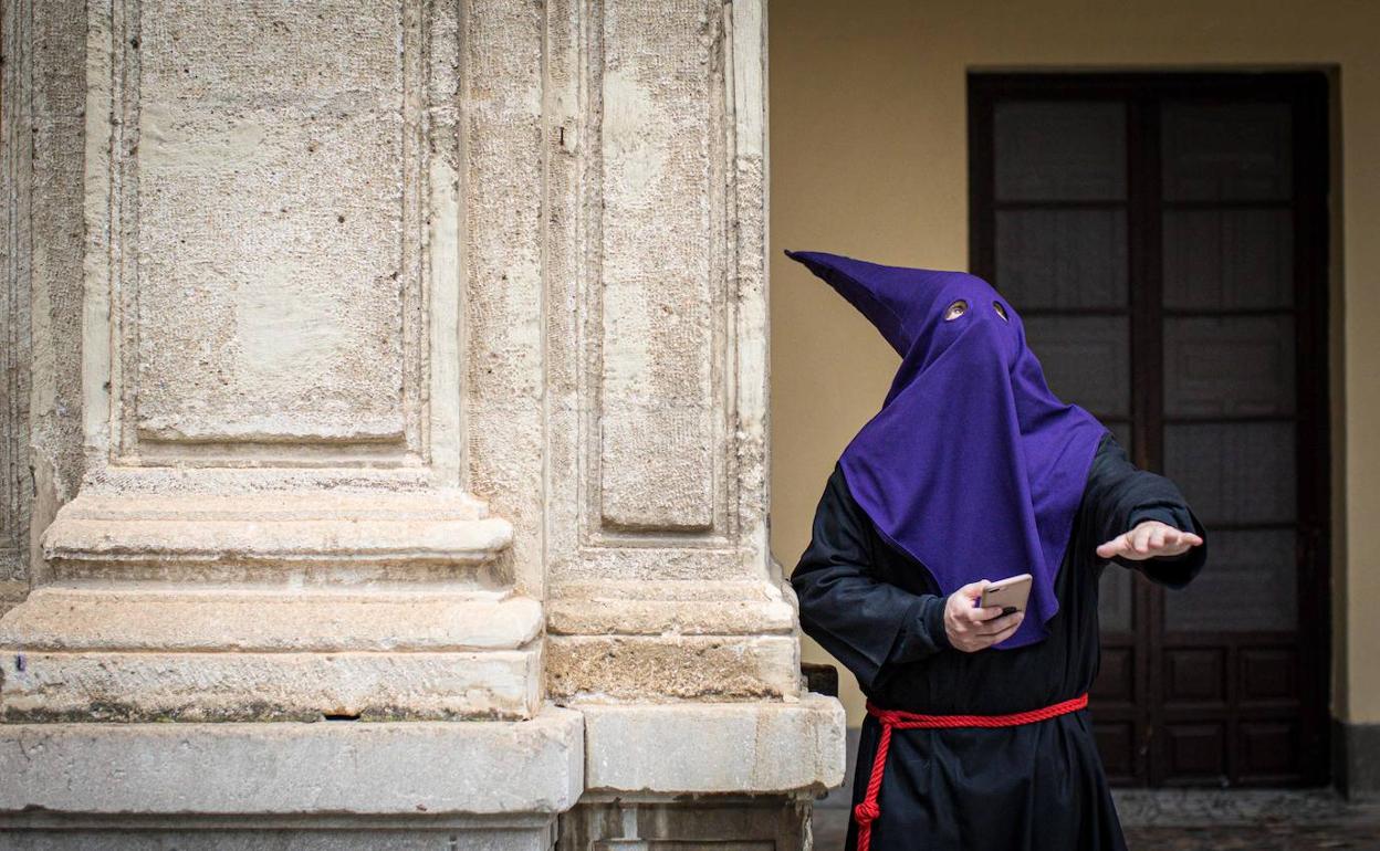 Un nazareno de la Humildad, pendiente del móvil y del cielo, comprueba si llueve. 