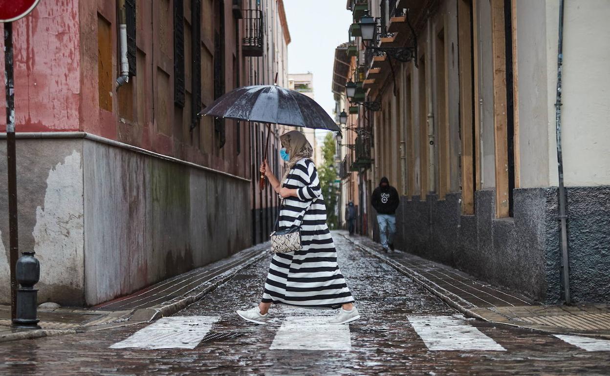 Una mujer caminando en Granada bajo la lluvia.