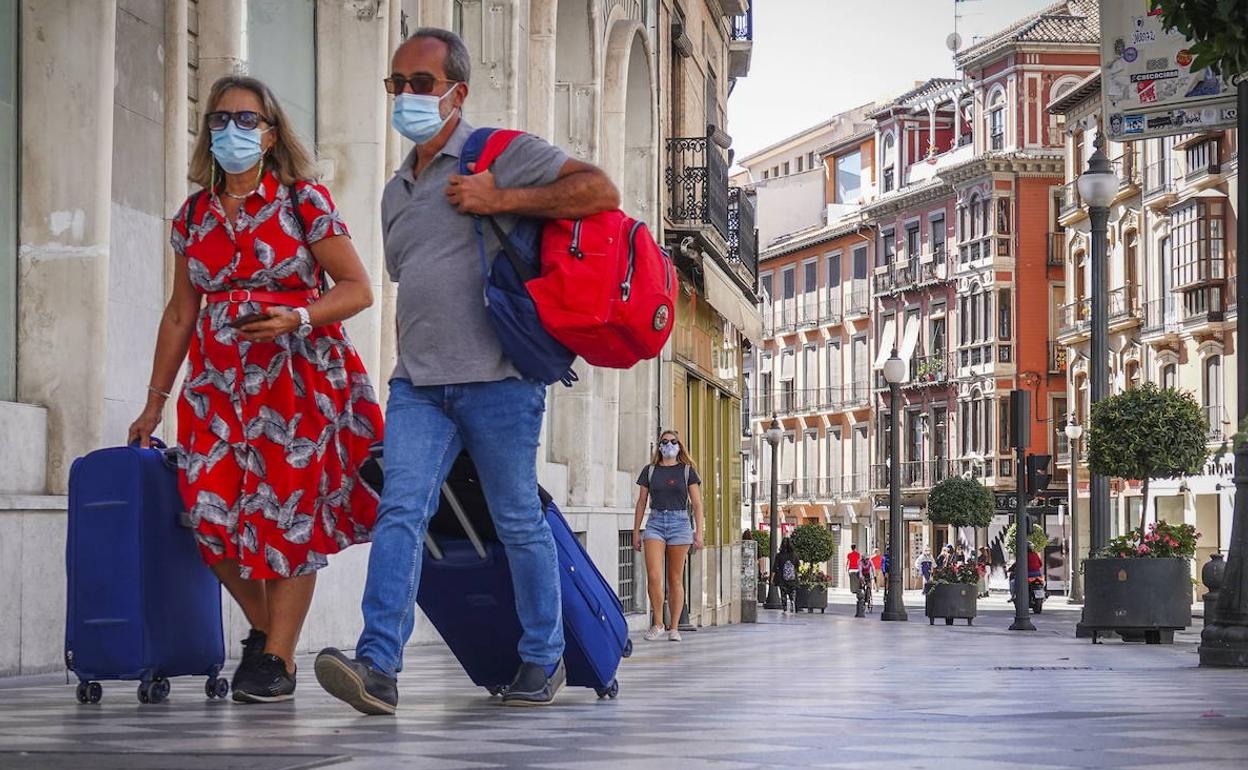 Una pareja de turistas recorre el Centro de la capital granadina con maletas en una imagen de archivo. 