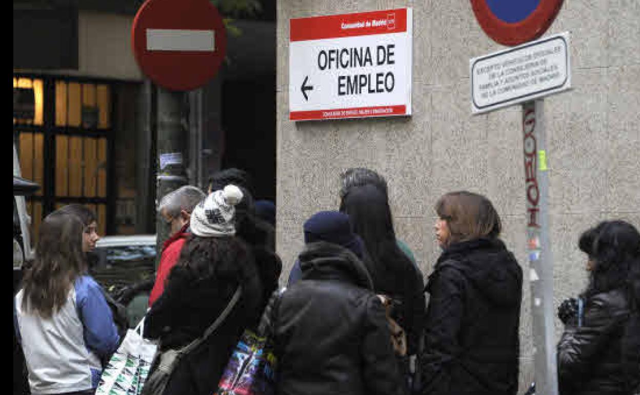 Un grupo de personas hacen cola a las puertas de una oficina de empleo. 