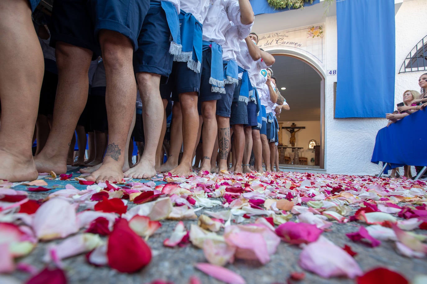 La Virgen del Carmen de Almuñéca, con el Barrio de Los Marinos al fondo, enfila la playa de San Cristóbal tras salir de la capilla.