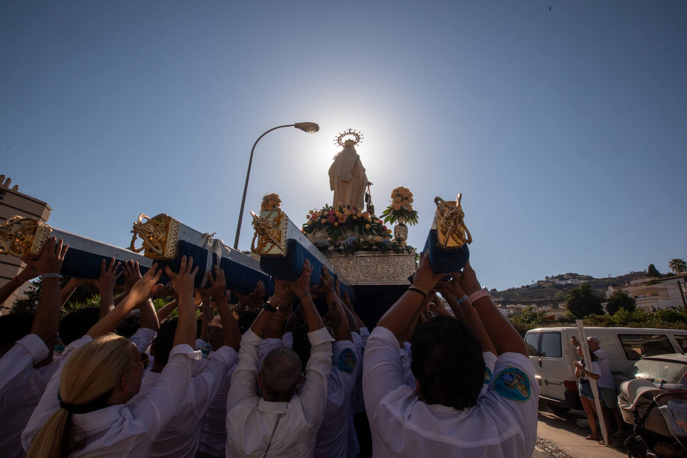 La Virgen del Carmen de Almuñéca, con el Barrio de Los Marinos al fondo, enfila la playa de San Cristóbal tras salir de la capilla.