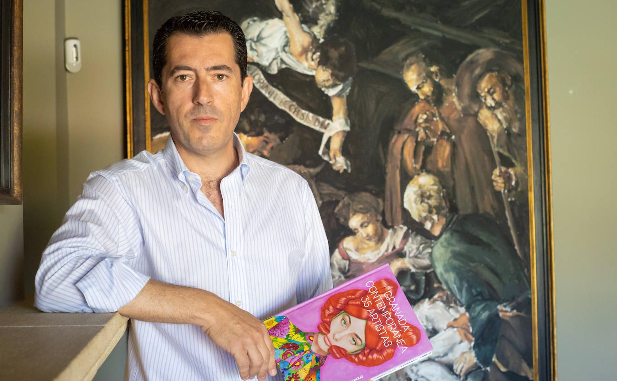 El ingeniero y coleccionista de arte Juan Alfonso Contreras, con su libro, ante una obra de Santiago Ydáñez.