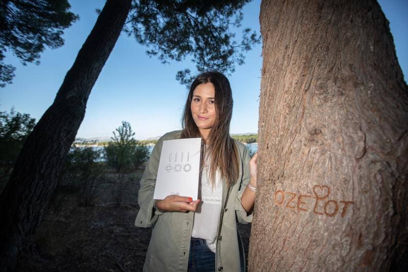 Patricia Valero muestra el libro en homenaje a su hermano junto al árbol en el que grabó su nombre. 