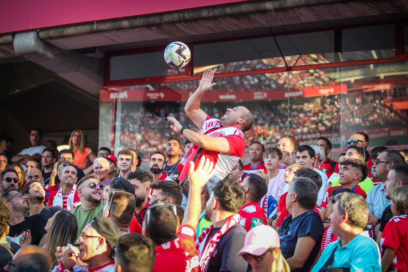 Un aficionado intenta atrapar un balón. 