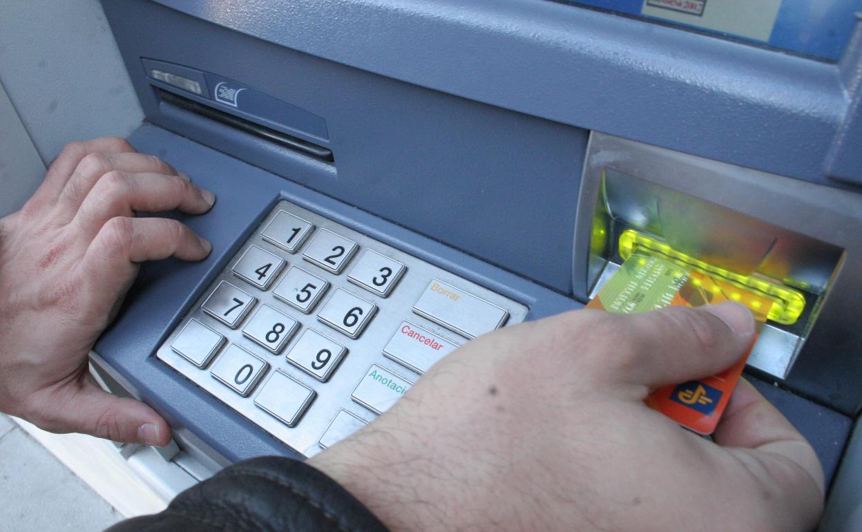 Un hombre introduce una tarjeta bancaria en el cajero automático