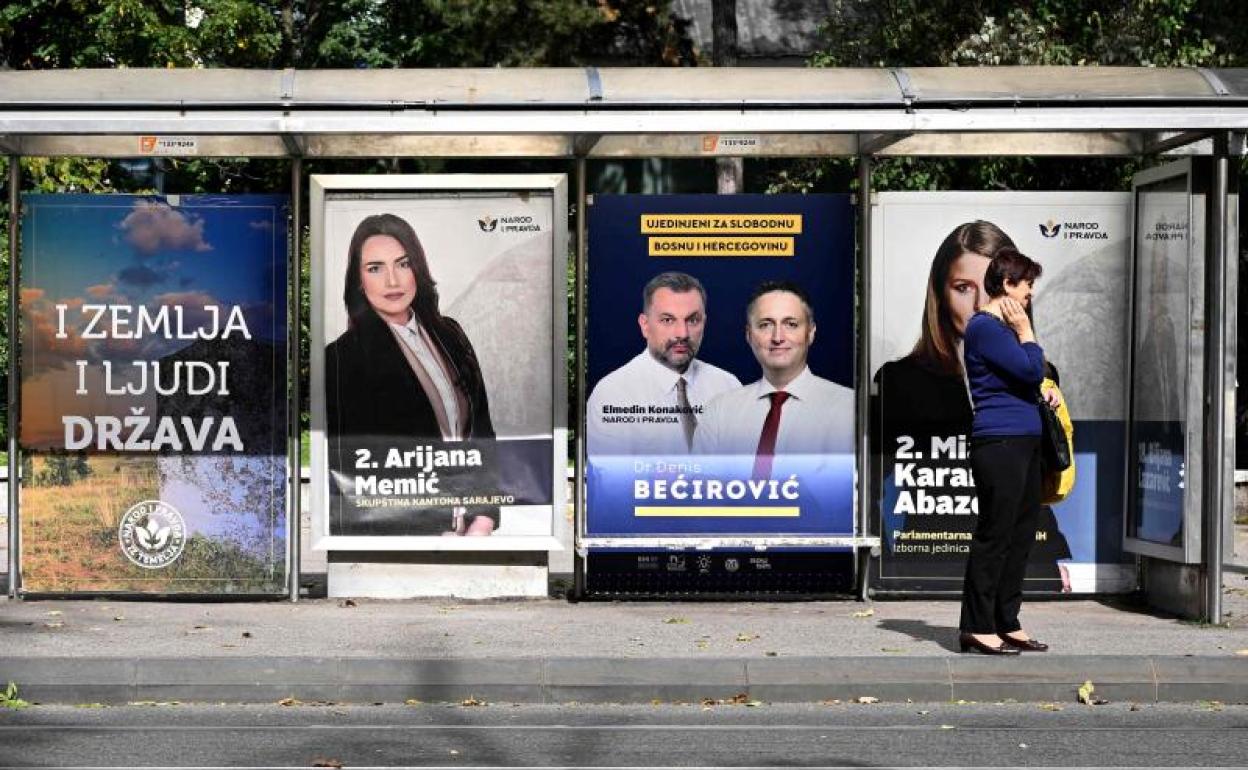 Una mujer espera en una parada de autobús de Sarajevo en la que se exhibe propaganda electoral. 