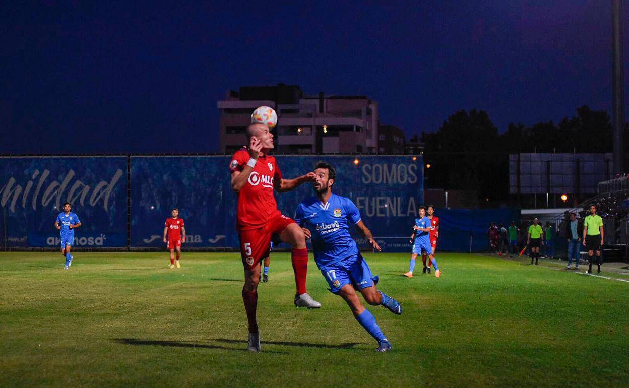 Lolo González ganando por arriba un balón ante la presión de un jugador local. 