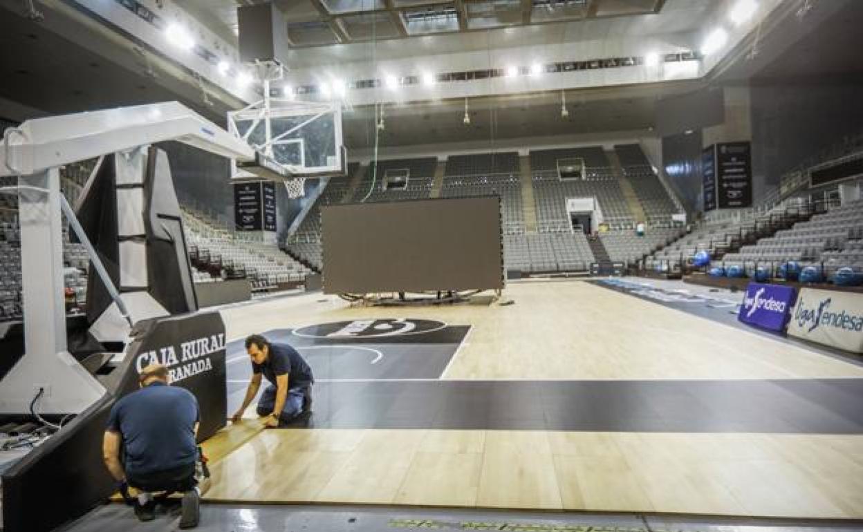 Operarios ajustan las tablillas de la pista del Palacio de Deportes tras las últimas modificaciones antes del retorno de Granada a la Liga ACB.