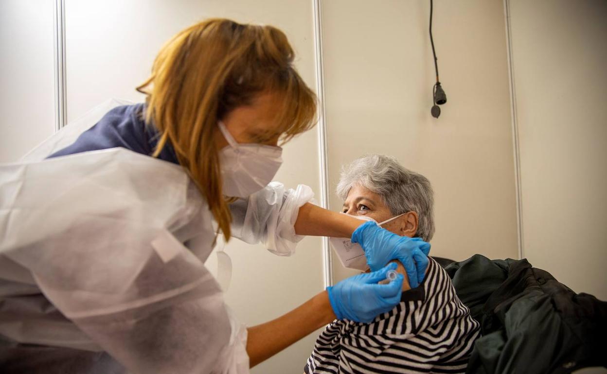 Una sanitaria vacuna contra la gripe a una mujer.