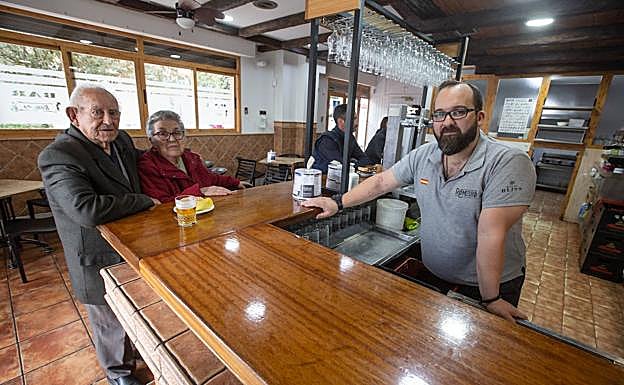 Imagen principal - Manuel, Filomena y Moisés, comparten anécdotas y recuerdos en la barra del bar Romero. Tatiana, a los mandos de la cocina. Manuel degusta la tapa que lleva su apellido.
