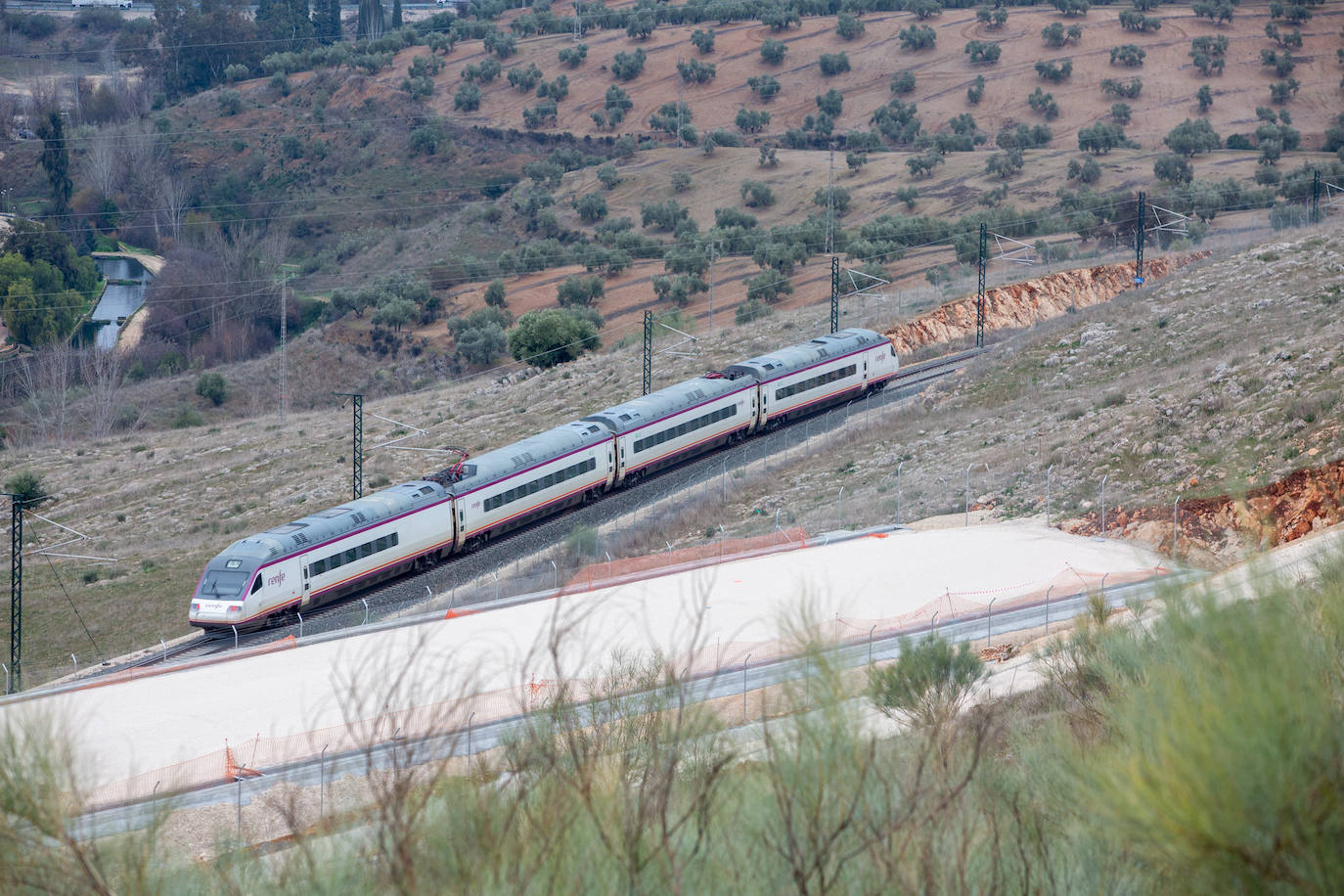 Un tren se cruza con las obras de la Variante de Loja.