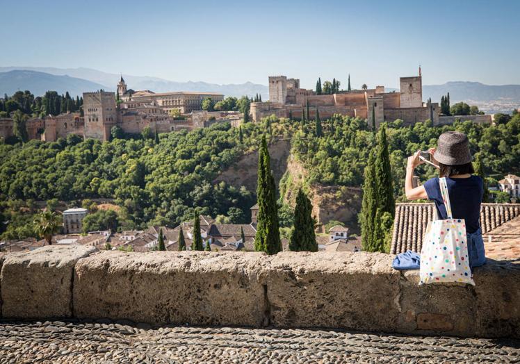 Un turista fotografía la Alhambra desde San Nicolás.