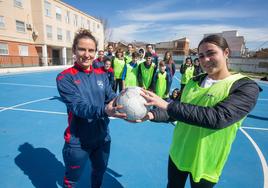 Urre, jugadora del Sima Granada femenino entrega un balón a una niña del instituto durante la jornada.