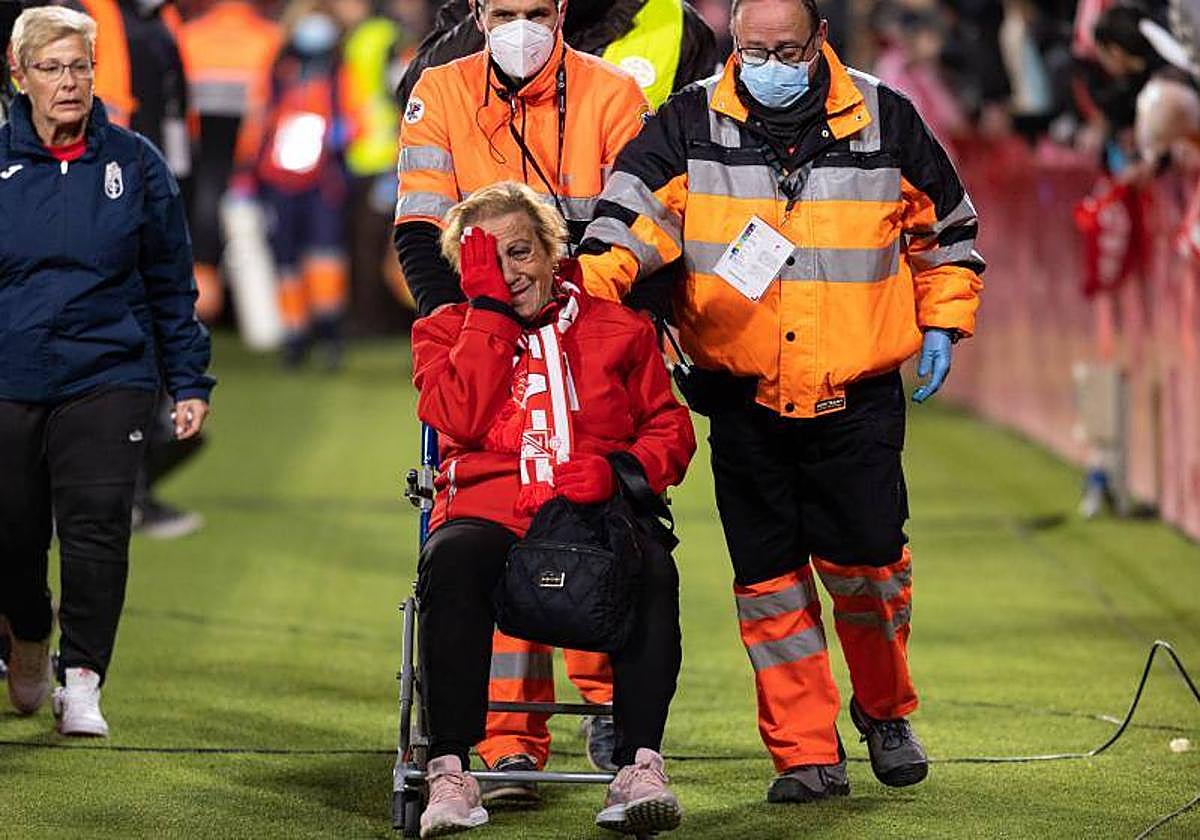 Una mujer es retirada en silla de ruedas entre lágrimas tras ceder la valla de la grada de animación.