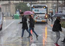 Personas cruzando la vía con lluvia.