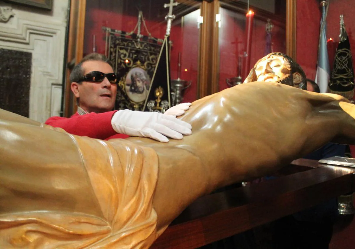 Agustín Fernández, palpa la talla del Cristo de la Buena Muerte.