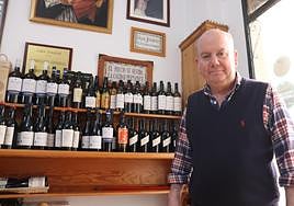 Joaquín Lópz posa frente a su bodega y el cartel «El precio se olvida. La calidad permanece».