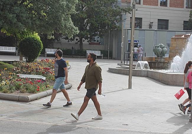 Dos jóvenes con pantalón corto y una botella de agua pasean por el centro de Jaén este jueves.
