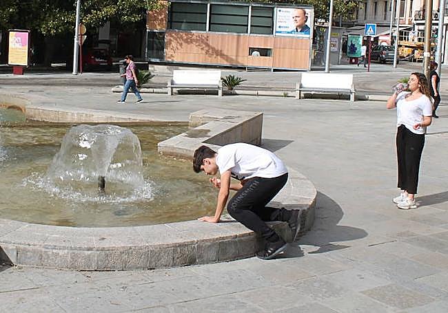 Un joven se refresca con el agua de la fuente de la Plaza de la Constitución.