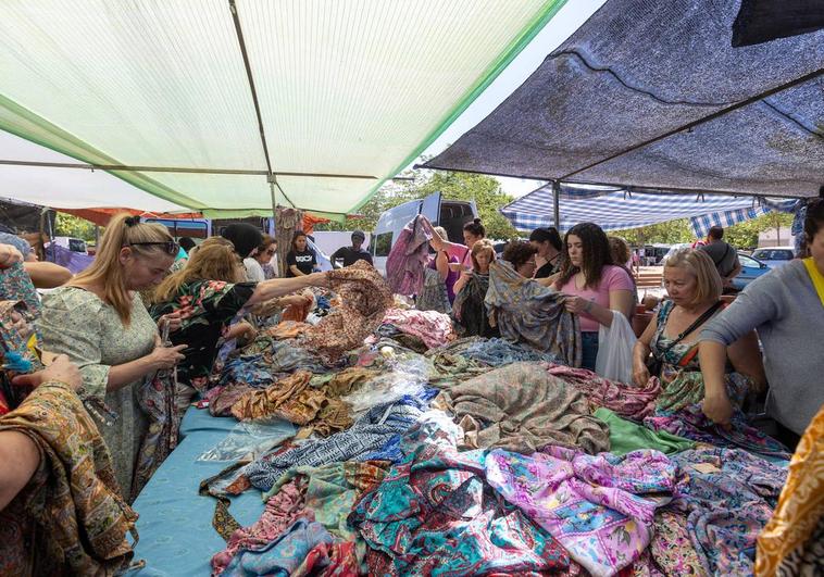 Un grupo de mujeres busca vestidos en un tenderete del mercadillo de Almanjáyar.