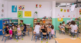 Niños de Infantil en un aula atendiendo las explicaciones de sus maestras.