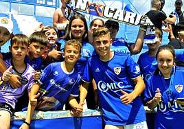 Fermín López posando con un grupo de niños en la grada, al finalizar un partido en Linarejos.