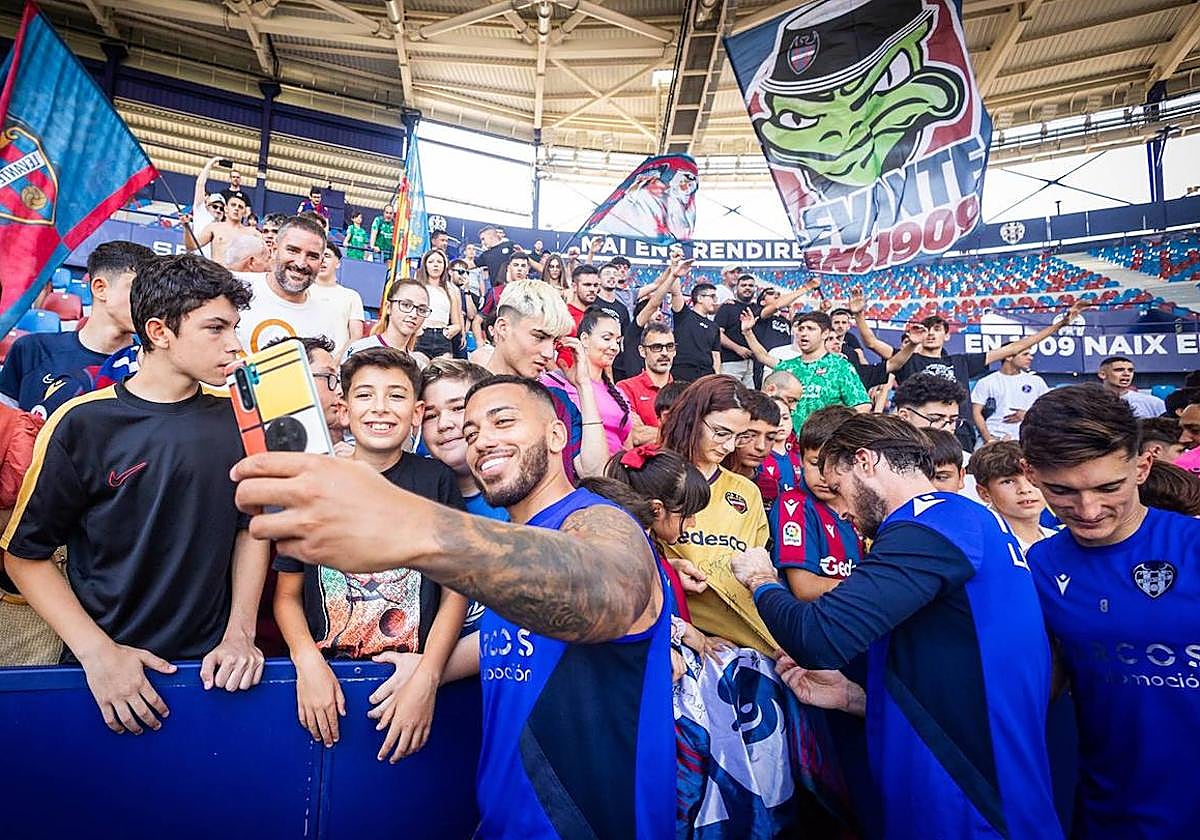 Los futbolistas del Levante se fotografían con aficionados durante el entrenamiento a puerta abierta del viernes.