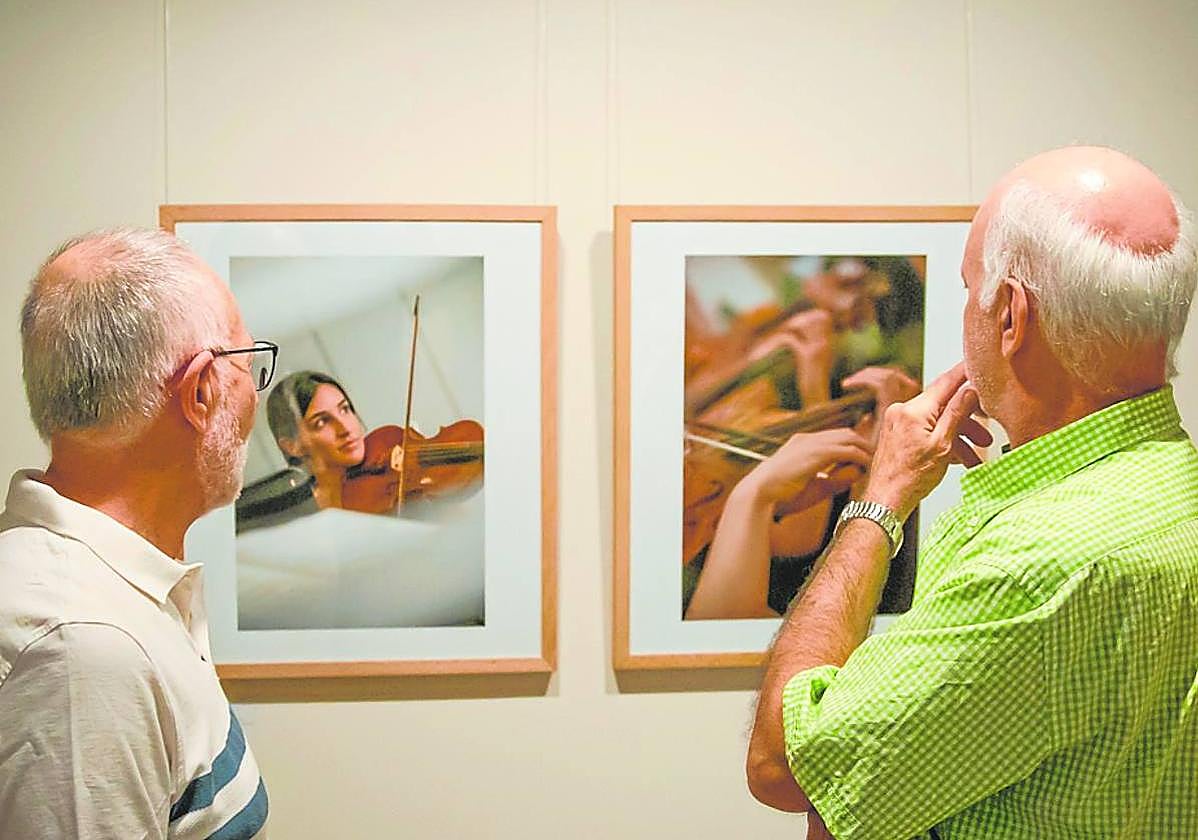 Dos asistentes observan algunas de las fotos de la exposición.