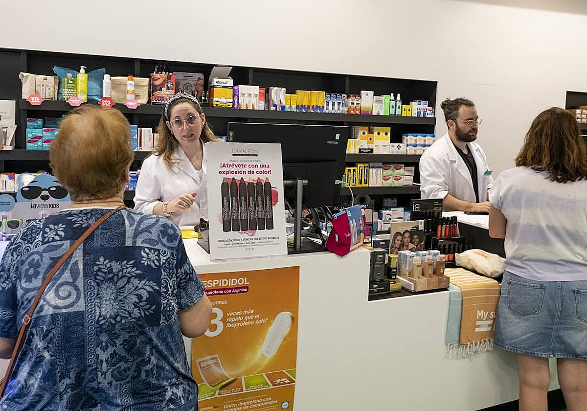 Dos farmacéuticos atendiendo a clientes.