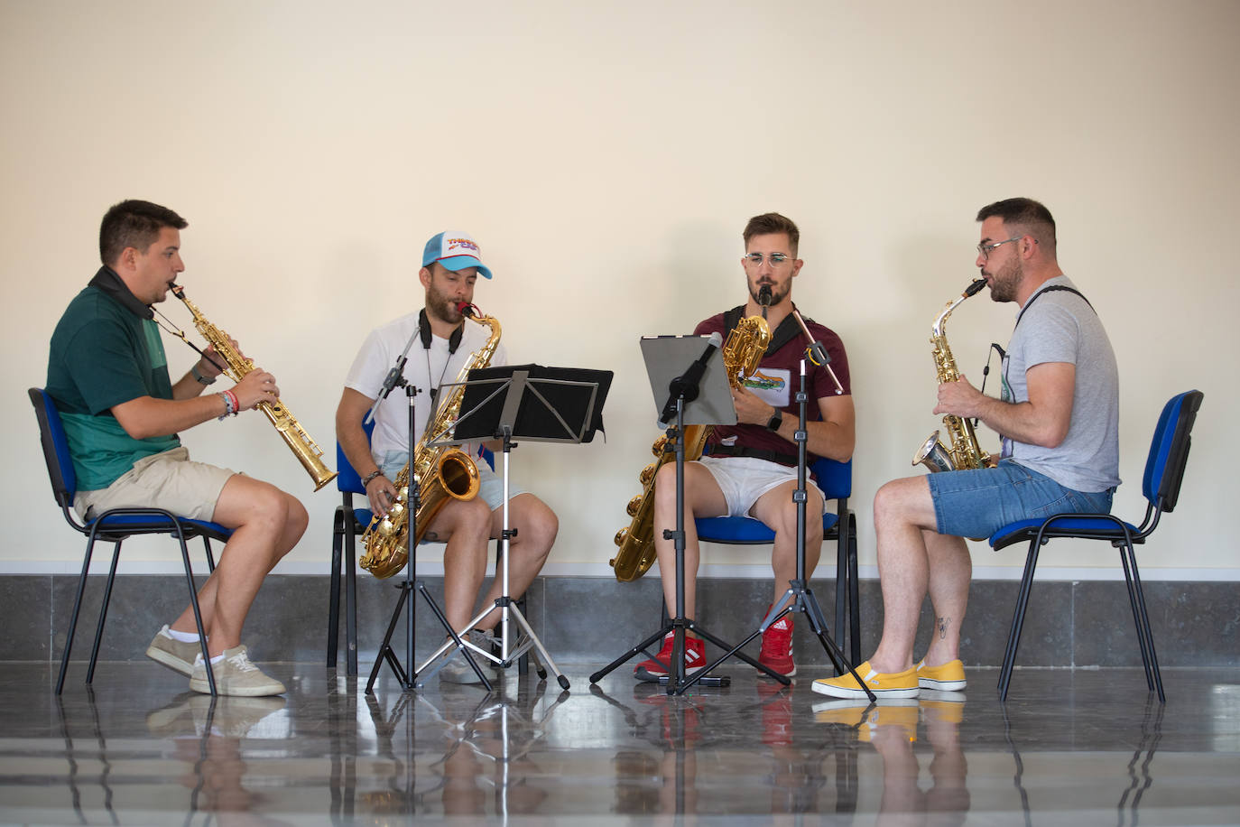 Imagen principal - Arriba, ensayo en la casa de la cultura. Abajo, reunión delante del estanco e iglesia con el crucero peregrino en primer plano. 