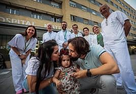 En primer plano, la pequeña Victoria junto a sus padres. Detrás, los profesionales sanitarios del Hospital Materno Infantil.