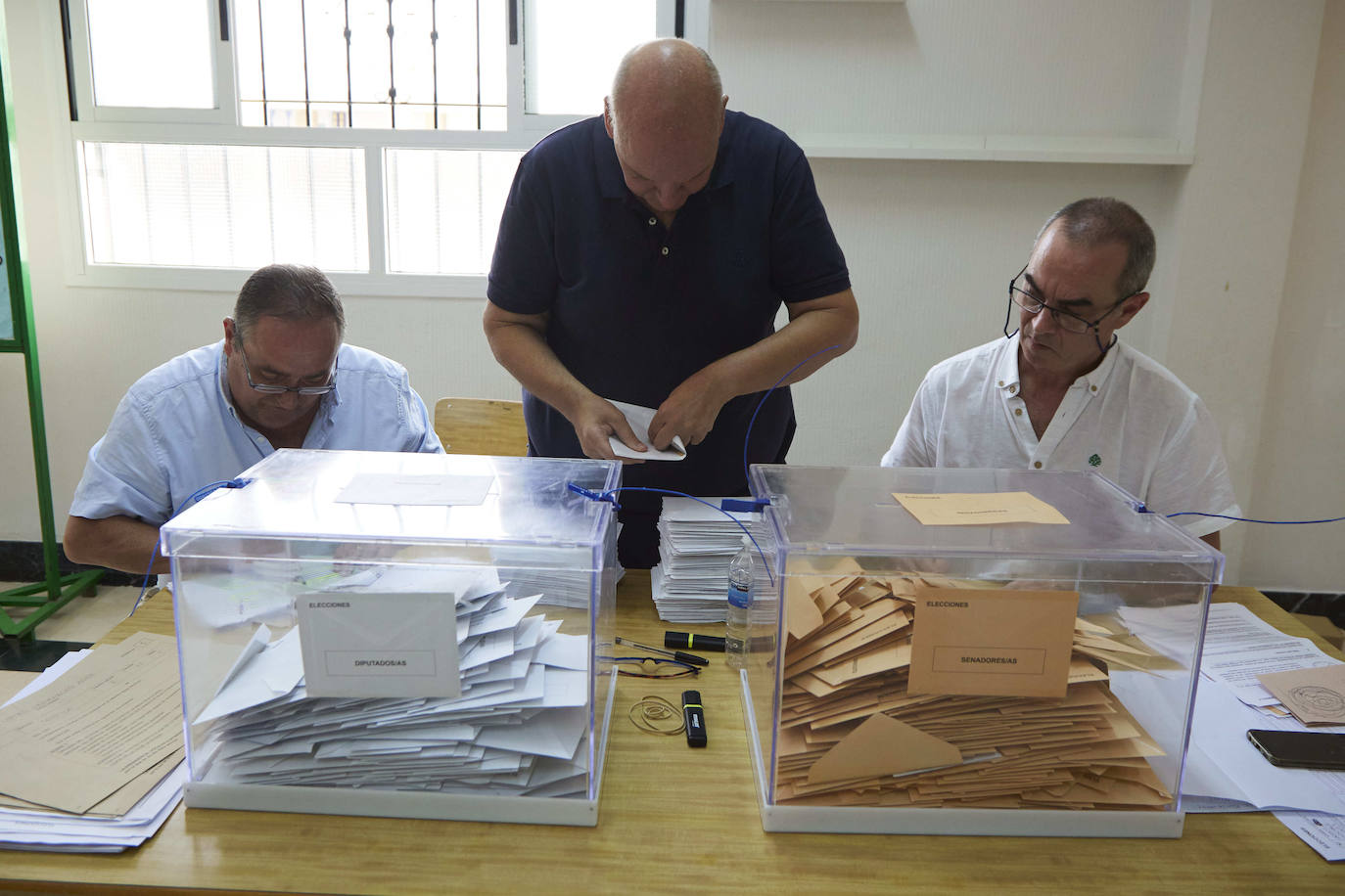 Los miembros de la mesa introducen el voto por correo en las urnas tras comprobar la inscripción de los electores.