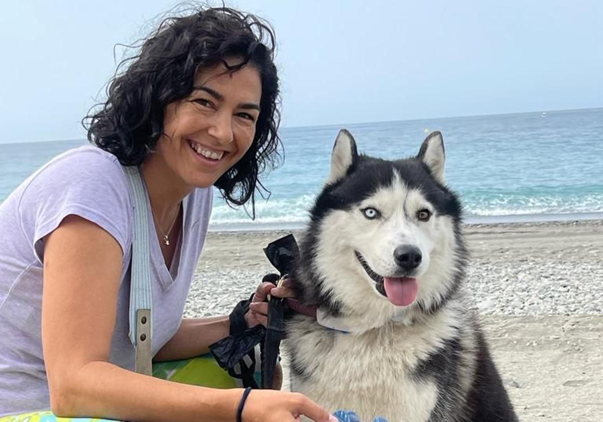 María José Rienda sostiene en la playa sus chanclas favoritas en presencia de su perro Husky.