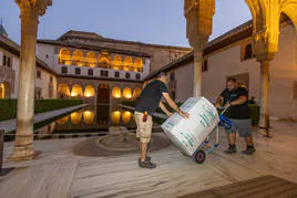 Operarios transportan una de las piezas por el Palacio de Comares, una imagen inusual en la Alhambra, llena siempre de turistas.