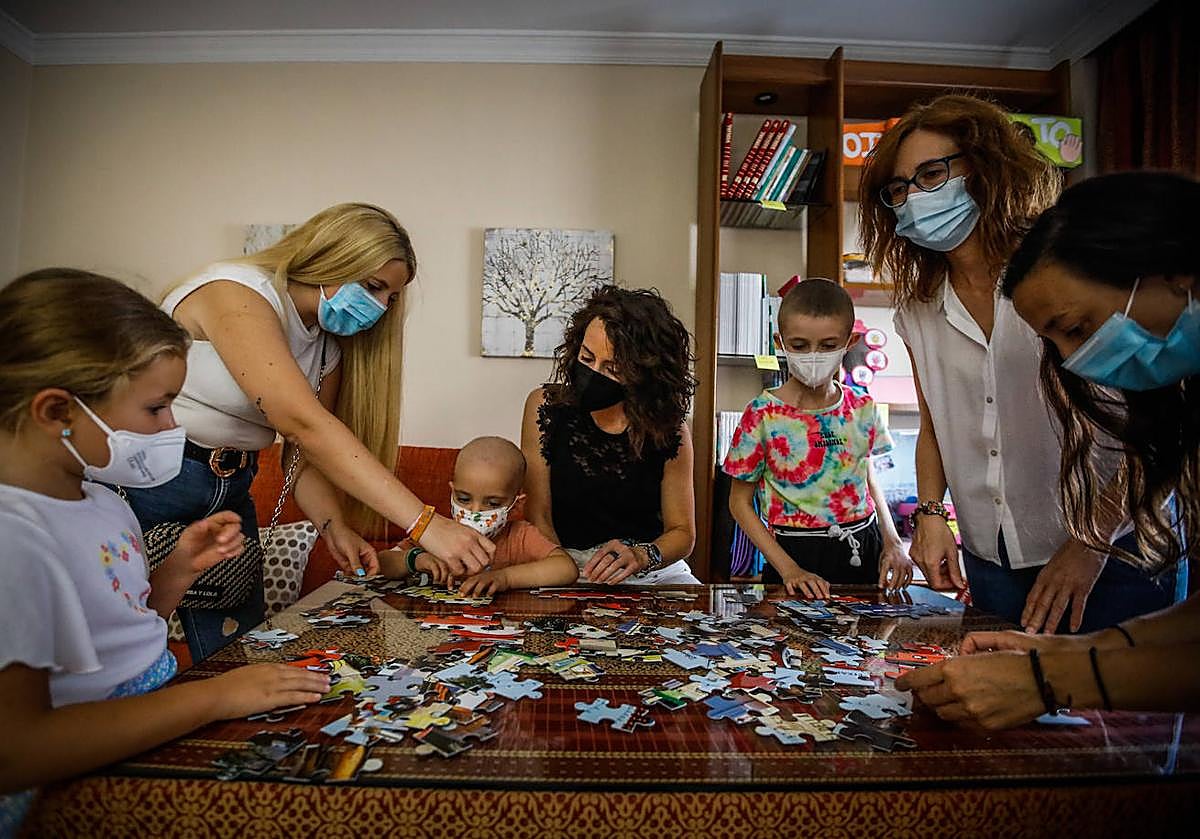 Menores con cáncer y sus familias juegan a un puzzle en la sede de la Asociación de madres y padres de niños oncológicos de Granada Aúpa.