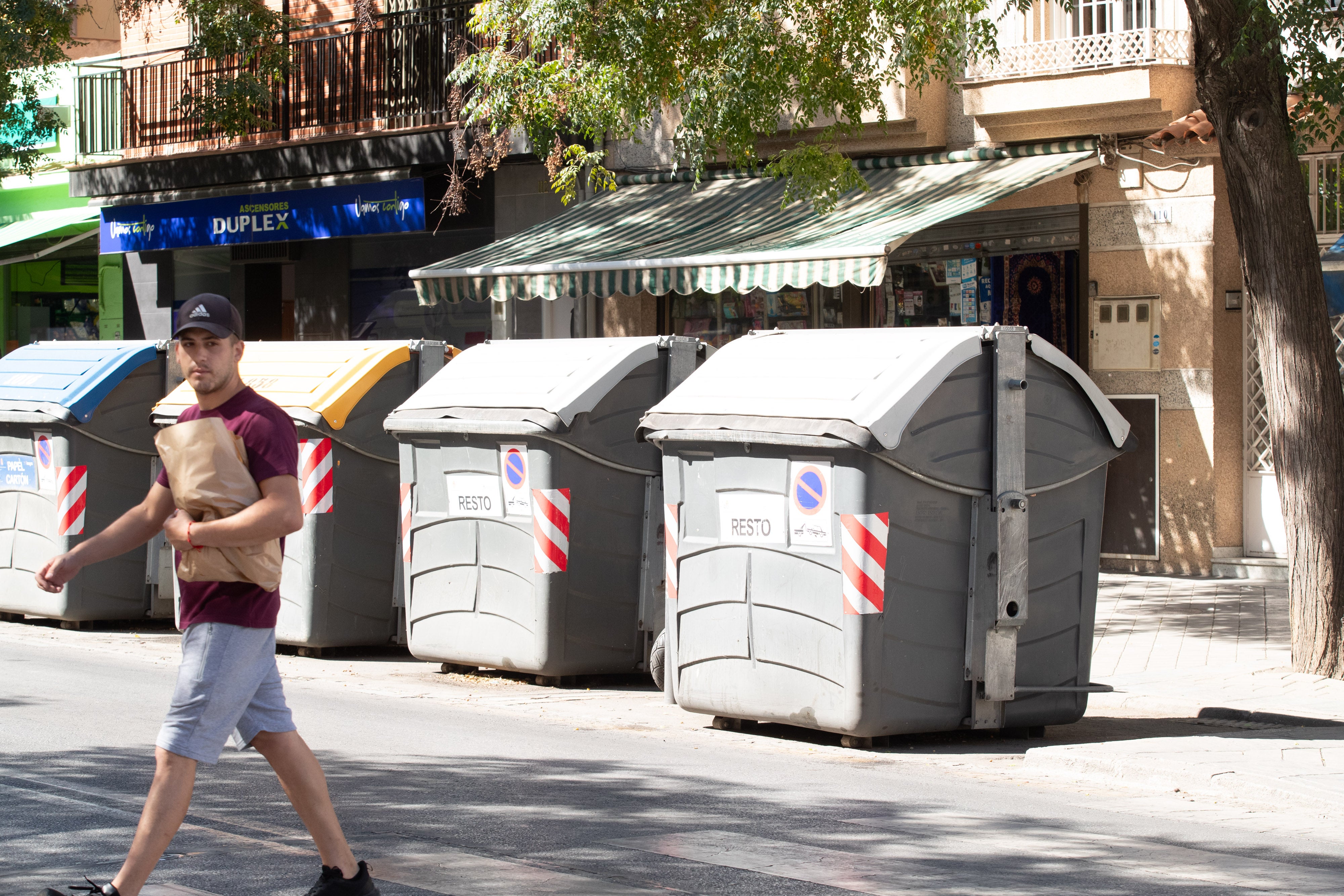 Una fila de contenedores delante de los negocios de la Avenida Dílar.