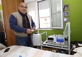 Un enfermo renal, muestra el aparato portátil con el que realiza la diálisis peritoneal en su casa.